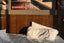 A bed with white pillows against a wood wall, lit by evening light