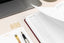 A planner and a task pad sit on a desk near a laptop computer