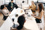 A group of five people sitting around a white meeting table.