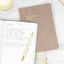 a daily reflection journal filled out with lessons, on top of another journal on a white table