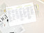 A busy filled in schedule on a white desk with a white magazine