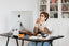 A woman sits at a desk and looks at her computer