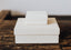Two white boxes stacked on a dark brown wood tabletop