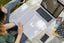 A woman sits outside with a laptop and a book