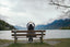 A woman sits on a bench in front of a lake
