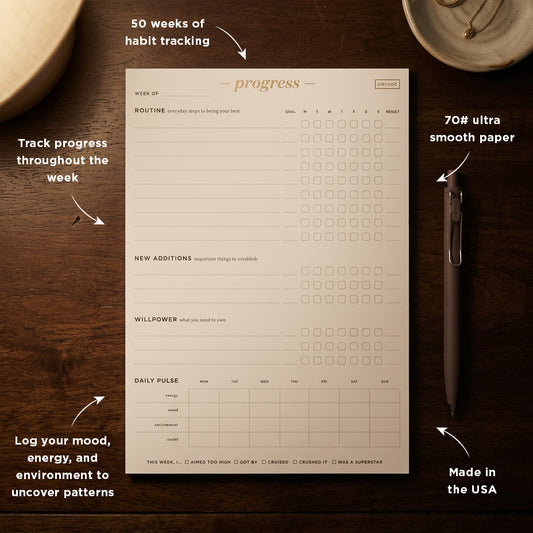  Habit tracking notepad with pen on a wooden surface
