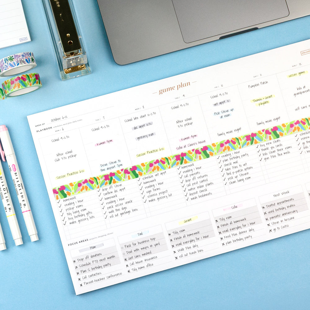 Colorful planner sheet with checkboxes on a blue surface with stationery items.